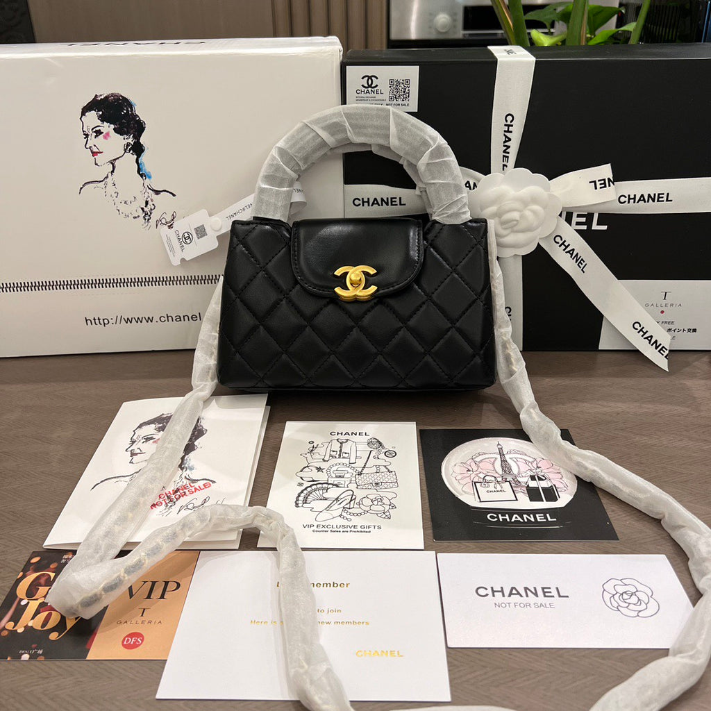 Black quilted handbag with gold clasp on a table with Chanel branded materials.