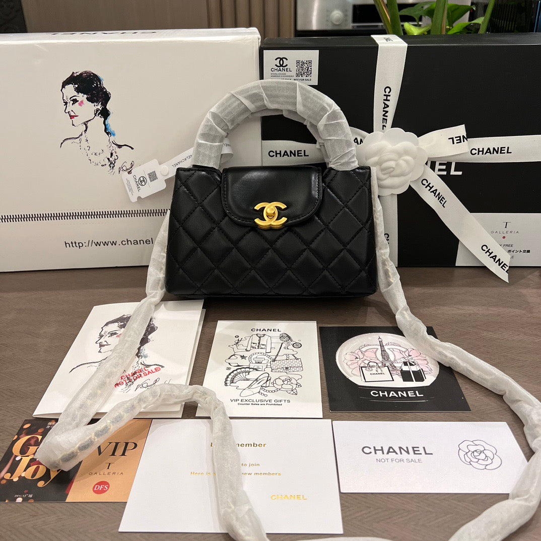 Black quilted handbag with gold clasp on a table with Chanel branded materials.
